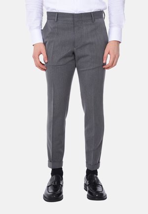 Pantaloni grigi su misura realizzati in tessuto tessuto, caratterizzati da una vestibilità slim, pieghe frontali e risvolti, abbinati a mocassini neri.