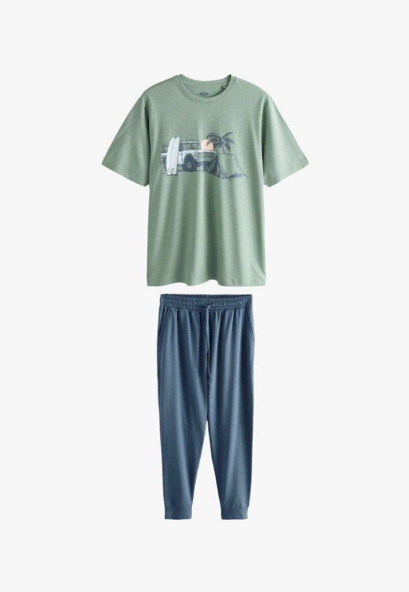 T-shirt vert clair à manches courtes avec motif de scène de plage, associé à un pantalon jogger bleu foncé avec cordon de serrage.
