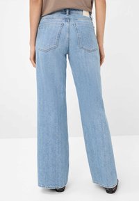 Jean large bleu clair à taille haute, doté de deux poches arrière et d'une texture lisse, avec un ourlet propre.