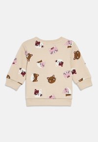 Majica z dolgimi rokavi kremne barve z teksturiranim vzorcem, na kateri so različni pisani obrazi mačk v roza, rjavi in beli barvi. Rebrasti robovi na manšetah in spodnjem robu.