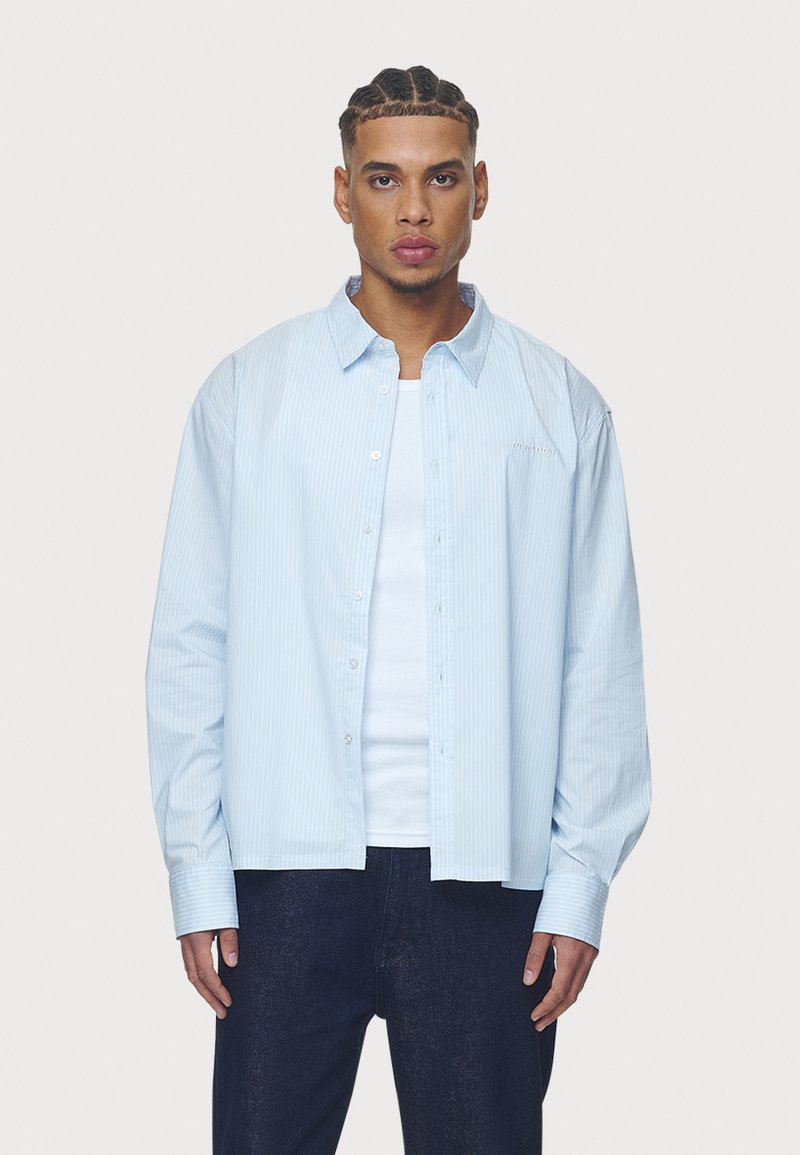 Svetlo modrá pruhovaná košeľa s dlhým rukávom vyrobená z bavlnenej látky, s button-down dizajnom, vo voľnom strihu a vyšívaným logom na hrudi.