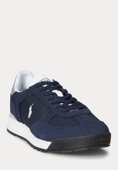 Marineblauwe Polo sneaker met suède en mesh panelen, wit logo aan de zijkant, zwarte veters en een wit-zwarte zool.