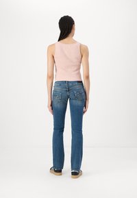 Light pink ribbed tank top with lace accents, paired with medium-wash blue flared jeans featuring back pockets and a casual fit.