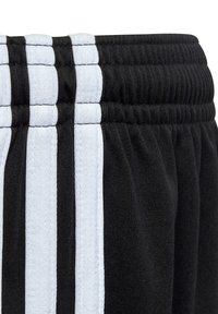 Černé sportovní kraťasy se třemi vertikálními bílými pruhy, vybavené strukturovaným elastickým pasem a hladkým materiálem.