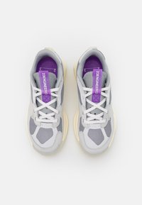 Gray mesh sneakers with a cream outsole, featuring purple accents on the tongue and laces, and a textured pattern on the upper.