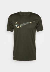Camiseta de manga corta verde oscuro hecha de una tela suave con un gran logo de Nike en patrón camuflaje en el pecho. Diseño clásico de cuello redondo.