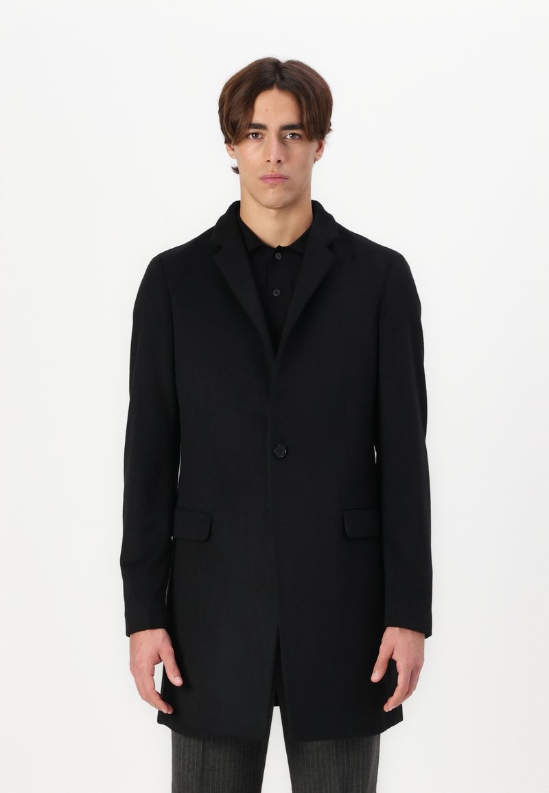 Cappotto nero; tessuto misto lana; chiusura con un bottone; rever con punte; due tasche frontali; vestibilità su misura; texture liscia; design lungo fino al ginocchio.