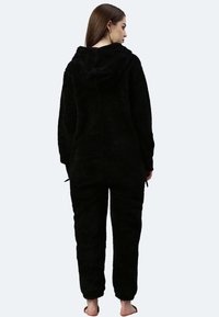 Schwarzer Kapuzen-Overall aus weichem, strukturiertem Stoff. Mit elastischen Bündchen und Hosen ausgestattet, bietet er einen lockeren Schnitt und ein gemütliches Design.