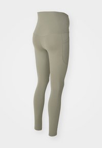 Leggings vert olive avec une taille haute, texture lisse et une poche latérale. Design ajusté avec une coupe slim et fuselée.