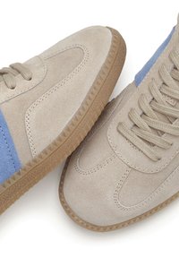 Beige Wildlederschuhe mit hellblauen Akzenten, runder Zehenpartie, strukturiertem Gummisohle und flachen Schnürsenkeln. Merkmale sind gestickte Details und Kontrastpaneele.