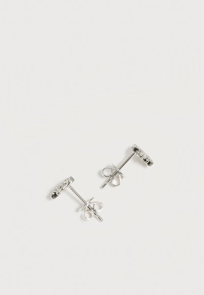 Paire de boucles d'oreilles clous en argent avec petites pierres précieuses transparentes, présentées sur un fond blanc uni.