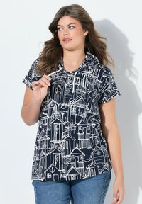 Camisa de manga corta en color navy con un patrón de casas de playa dibujadas en blanco, con capucha y detalle de cordón delantero. Textura de tela suave.