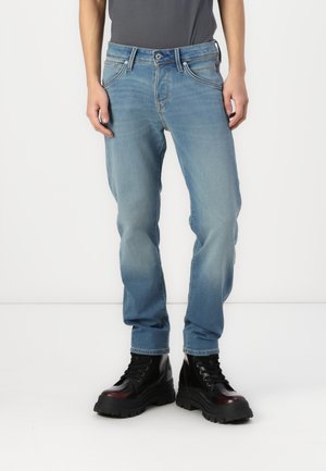 Light blue denim jeans with a regular fit, featuring a classic five-pocket design and a button closure. Worn with black chunky boots.