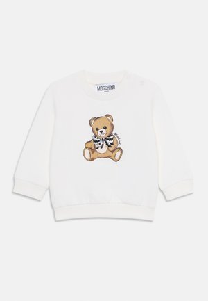 Sudadera blanca con un gráfico de un oso de peluche que lleva una pajarita en blanco y negro. Incluye botones a presión en un hombro para facilitar el vestirse.