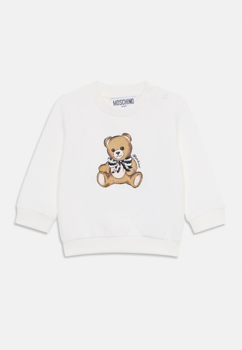 Sweatshirt blanc avec un motif de ours en peluche portant un nœud papillon noir et blanc. Comprend des boutons-pression sur une épaule pour un enfilage facile.