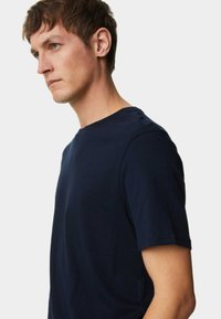 Camiseta de cuello redondo en azul marino, hecha de un suave tejido de algodón, con mangas cortas y un diseño liso sin estampados ni adornos.
