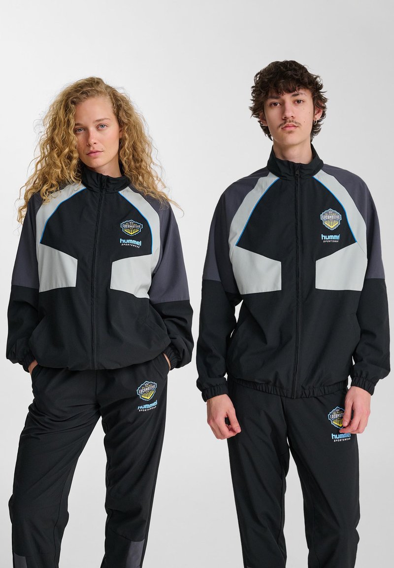 Svart och grå sportiga träningsdräkter med zippered jackor och elastiska byxor; med logotypdetaljer och färgblockerat mönster.
