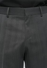Formele grijze broek met een visgraatpatroon, een gladde textuur, riemlussen en een getailleerde pasvorm bij de taille.