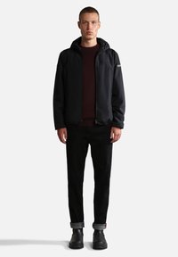 Sort zip-up jakke med hætte, båret over en bordeaux sweater. Sorte jeans og sorte støvler fuldender outfittet. Enkel design uden synlige mønstre.