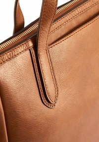 Brązowa skórzana torba tote o teksturowanej powierzchni, smukłym designie, z dwoma solidnymi uchwytami i złotym zamkiem błyskawicznym na górze.