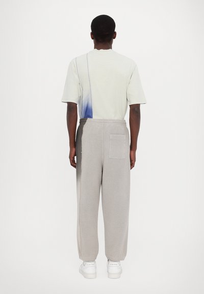 Light grey sweatpants with a textured fabric, elastic waistband, and side pocket, paired with a short-sleeved, soft green and blue gradient shirt.