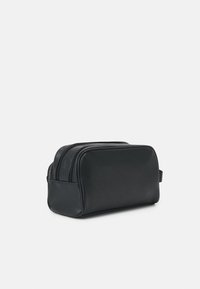 Black leather toiletry bag with a rectangular shape, double zipper closure, side handle, and smooth texture. Simple, sleek design.