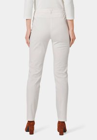 Licht beige slim-fit broek met een soepele textuur, met een hoge taille en minimalistisch ontwerp, gecombineerd met donkerbruine suède blokhakken.