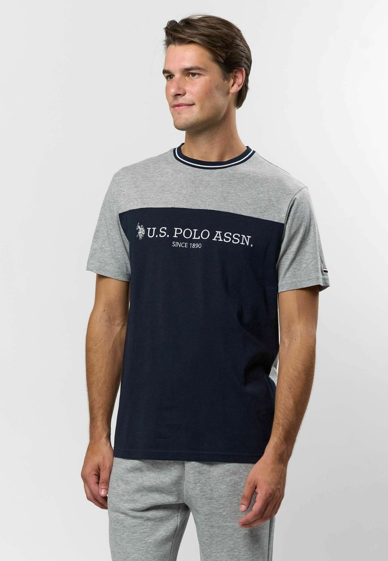 Granatowa i szara koszulka z krótkim rękawem z logo U.S. Polo Assn., okrągły dekolt, a dolna część koszulki w jednolitym granatowym kolorze. Miękki materiał z bawełny.