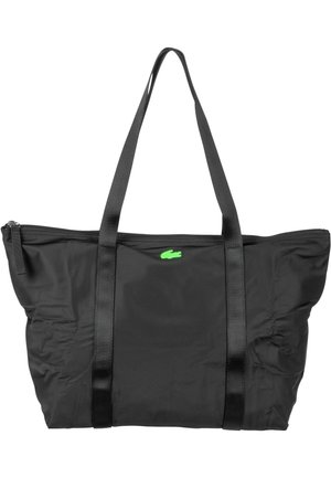 Sac cabas en nylon noir avec deux anses noires, fermeture éclair et un petit logo de crocodile vert à l'avant. Texture lisse avec une structure souple.