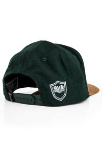 Green wool cap with a brown brim; features a white embroidered shield logo on the back, adjustable plastic strap closure.