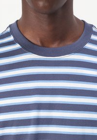 Korte mouwen marineblauw T-shirt met horizontale strepen in lichtblauw en wit. Ribbelboord ronde hals; katoenmix stof met een gladde textuur.