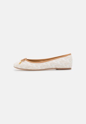 Chaussure de ballet plate beige avec motif texturé, bordure tan, petit nœud sur l'avant et détail de breloque dorée sur fond blanc.