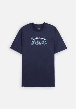 T-shirt en coton bleu marine avec un logo "OXBOW" central entouré de motifs de feuilles vertes, manches courtes et col rond.