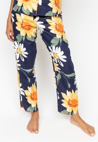 Navy pants with large yellow sunflowers and white daisies. Smooth fabric, straight leg design, and orange trim along the hem.