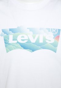 Camiseta blanca de algodón con un colorido logo de Levi's que presenta un diseño de paisaje, incluyendo montañas y nubes en tonos azules y verdes.