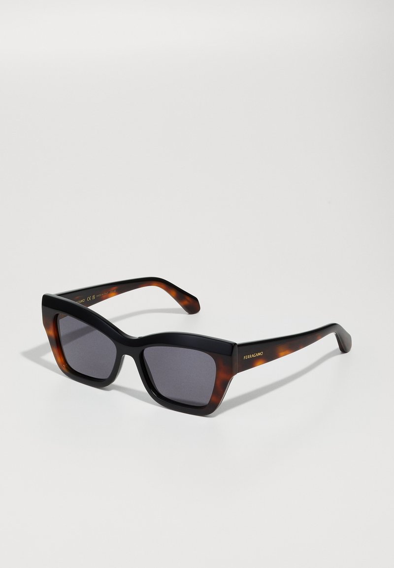 Occhiali da sole rettangolari in nero e tartaruga con lenti grigie, dotati di un design robusto e un sottile dettaglio del logo sulla asta.