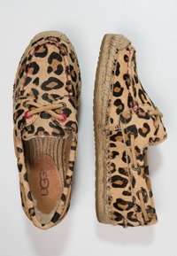 Leren mokassin met luipaardprint, beige basis, leren veters, gevlochten jute details en een zachte, gevoerde binnenschoen.