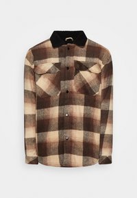 Camicia a quadri nei toni del marrone, crema e scuri. Realizzata in tessuto morbido, presenta un colletto in pile nero e due tasche sul petto. Chiusura a bottoni.
