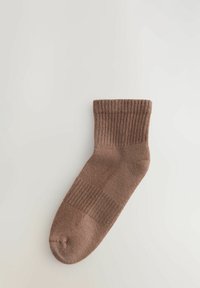 Brun bomullssocka med ribbad kant, slät textur och förstärkt häl. Har en klassisk form och en enfärgad nyans utan mönster.