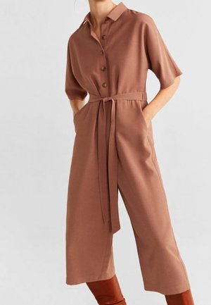 Brauner Jumpsuit mit Gürtel, kurzen Ärmeln, Knopfleiste vorne und Seitentaschen. Hergestellt aus glattem Stoff; verfügt über einen Kragen und ein weit geschnittenes Bein.