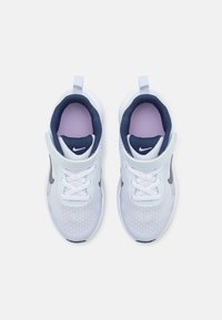 Baskets de sport bleu clair avec tige en mesh, accents navy, lacets blancs, doublure intérieure violette et un logo noir sur le côté.