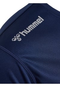 Marineblauwe sporttrui met een gestructureerde stof, gebogen naden en een zilveren logo. De kraag is rond en de stof heeft een ademend patroon.