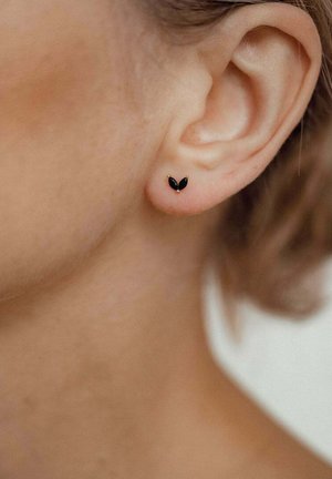 Orecchini in metallo nero a forma di ali di farfalla, con una finitura liscia e dettagli dorati nei punti di attacco.