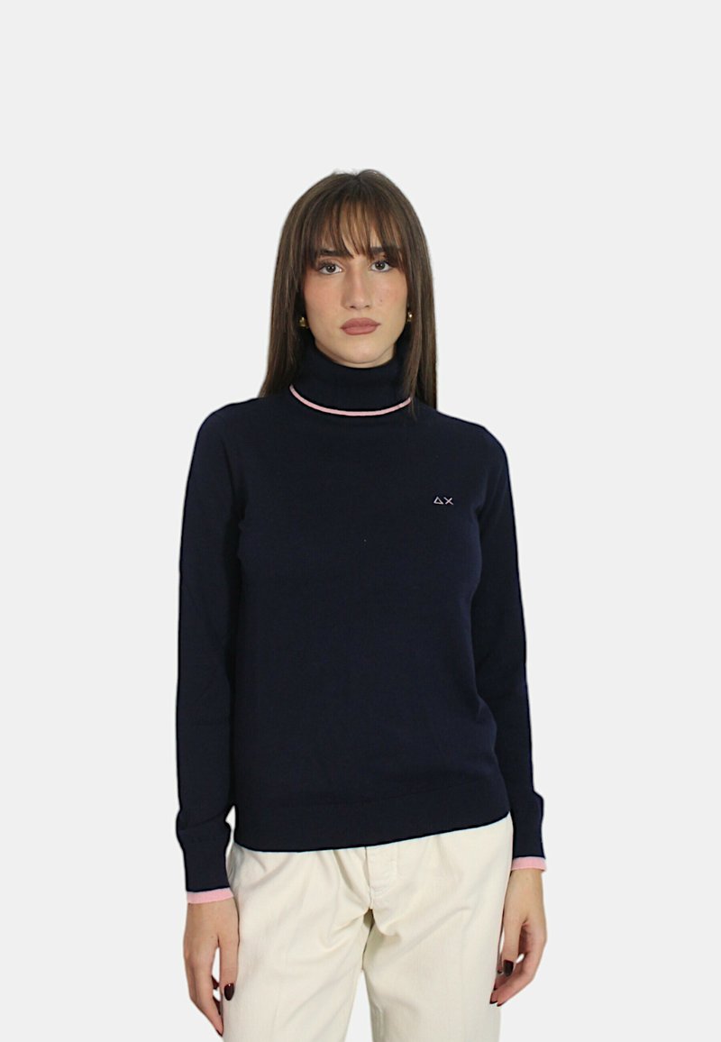 Maglione a collo alto blu navy con accento rosa al colletto, caratterizzato da un piccolo logo sul lato sinistro. Realizzato in materiale morbido ed elasticizzato.