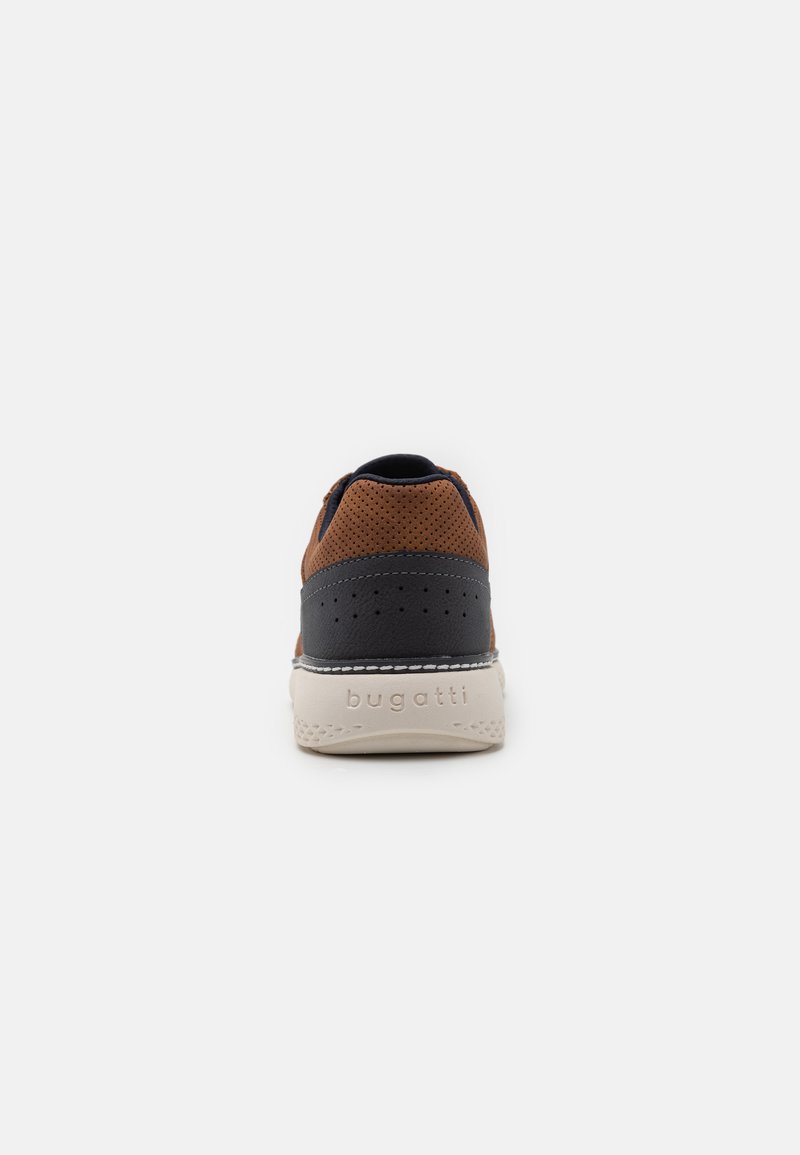 Sneaker en cuir marron et tissu bleu marine avec des détails perforés, semelle blanche et "bugatti" embossé sur le talon. Design arrondi.