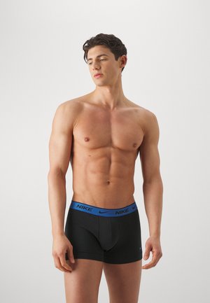 Boxer briefs neri con un cinturino blu con il marchio Nike, caratterizzati da una vestibilità aderente e materiale morbido. Il modello è in piedi con un'espressione neutra.