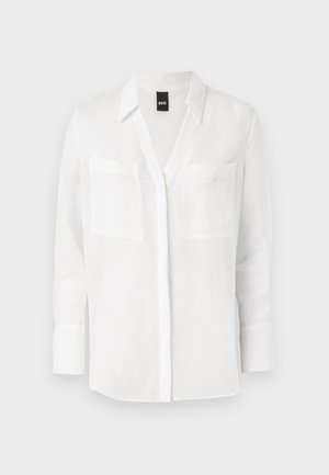 Biała, długa koszula z lnu z dekoltem w serek, dwoma kieszeniami na piersi i mankietami na guziki, charakteryzująca się czystym, minimalistycznym stylem.