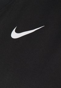 Camiseta de tela negra con una textura suave que presenta un prominente logo de Nike en blanco en el frente. Diseño sencillo, de mangas cortas.