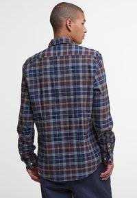 Męska koszula w kratę z długim rękawem w kolorach granatowym, bordowym i jasnoszarym. Posiada mankiety na guziki, klasyczny kołnierz oraz zaokrąglony tył.