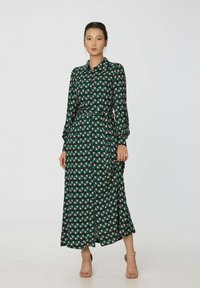 Robe longue à boutons en polyester vert avec un motif en grille rose et blanc. Elle possède des manches longues, une ceinture et une coupe décontractée.